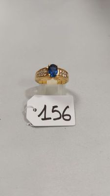 Gros plan sur une bague en or ornée d'une pierre bleue