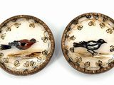 une paire de petits oiseaux en céramique posés sur une surface blanche