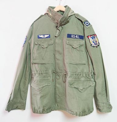 une photo d'une veste verte ornée d'écussons, suspendue à un cintre