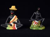 deux figurines représentant un homme coiffé d'un chapeau et une femme assise sur une souche d'arbre