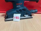 une ponceuse orbitale Bosch posée sur une table, avec son étiquette de prix