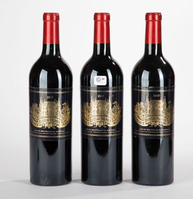 trois bouteilles de vin rouge posées l'une à côté de l'autre sur une surface blanche