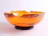 un bol orange posé sur un socle noir, lui-même posé sur une surface blanche