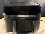 une friteuse à air chaud posée sur une table en bois, à côté d'un sac en plastique