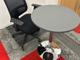 une chaise noire et une table grise dans un coin de la pièce