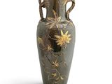 a green vase with gold flowers on it on a white background