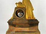 a gold clock with a statue on top of it