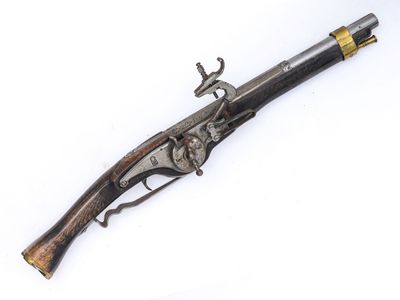 un vieux pistolet avec une poignée en bois sur une surface blanche