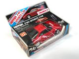 une petite voiture rouge dans une boîte sur une surface blanche