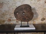 une sculpture en pierre posée sur une table devant un mur de pierre