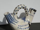 a blue and white bird shaped vase sitting on a table