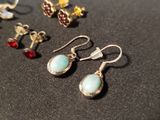 several pairs of earrings are sitting on a black surface