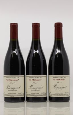three bottles of red wine are lined up on a reflective surface