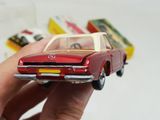 a hand holding a red toy car in front of other toy cars