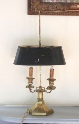 a lamp that is on a table with a painting on the wall behind it