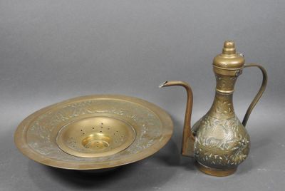 a brass tea pot and a brass plate on a table