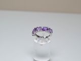 a close up of a ring with purple stones on a white surface