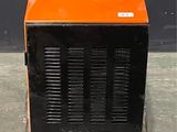 un radiateur portable orange et noir posé sur un sol en béton