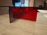 a glass table with a red top on a tile floor