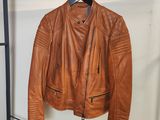 une veste en cuir marron suspendue à un porte-manteau dans une pièce