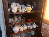 a wooden cabinet with many dishes and cups on it