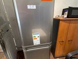 a silver refrigerator in the corner of a room with a black chair