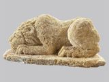 une sculpture en pierre représentant un chien couché par terre