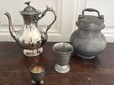 une théière en argent et une tasse en argent posées sur une table en bois