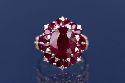 un gros plan d'une bague sertie d'un rubis et de diamants sur un fond bleu