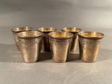 six silver shot glasses lined up in a row on top of a table