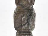 un vase en pierre posé sur un socle en bois, sur fond blanc