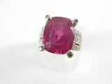 un gros plan d'une bague ornée d'une pierre rose sur un fond blanc