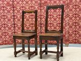 two wooden chairs sitting next to each other in a room