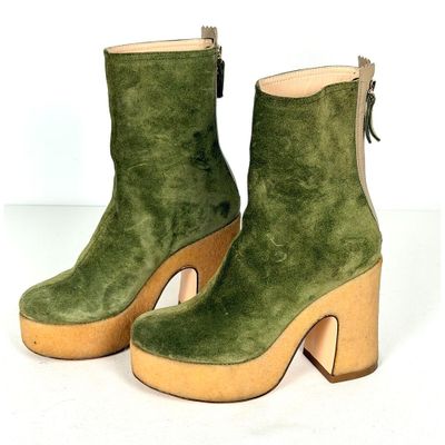 paire de bottes en daim vert à talon en bois sur fond blanc