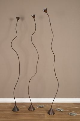 Deux grands lampadaires en métal sont posés devant un mur marron