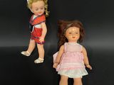 two small dolls are standing next to each other on a black surface
