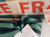 a green and blue striped pillow with a tag on it