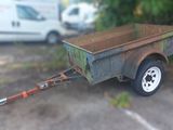 une petite remorque à laquelle est attelée une autre remorque, dans un parking