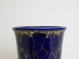 a close up of a blue vase on a white surface