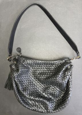 a gray and black purse with a tassel hanging from the handle