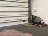un sac noir posé sur une palette devant la porte d'un garage