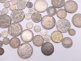 a pile of old silver coins on a white surface