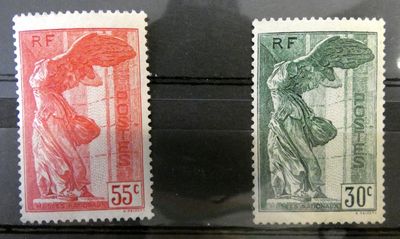 Deux timbres de couleurs différentes sont exposés dans une vitrine.