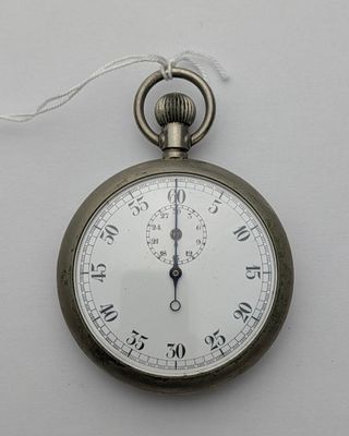 une montre de poche en argent accrochée à un mur blanc