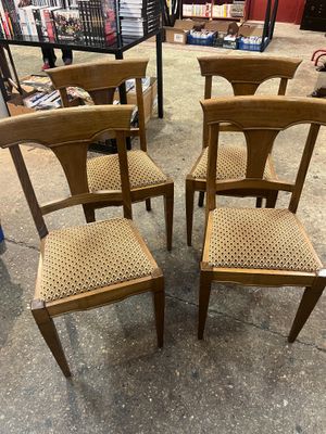 four wooden chairs with woven seats in a store