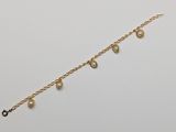 un gros plan sur un bracelet en chaîne dorée orné de perles