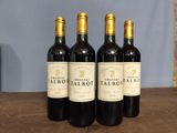 three bottles of red wine sit on a table in front of a blue wall