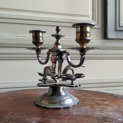 un candélabre en argent posé sur une table en bois devant une fenêtre