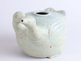 a small vase with a bird on it on a white surface
