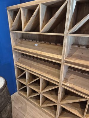 Les étagères sont en bois et contiennent de nombreuses bouteilles de vin.